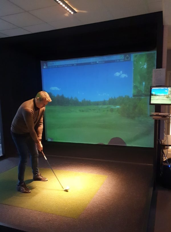 Mann som spiller golf i en golfsimulator